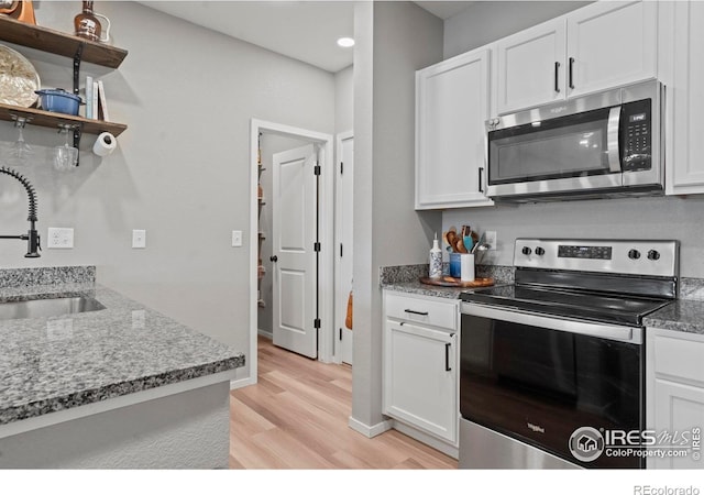 3644 Ronald Reagan Ave, Wellington, CO 80549 - kitchen with stainless steel appliances, open shelves, light wood-type flooring, white cabinetry, and stone countertops