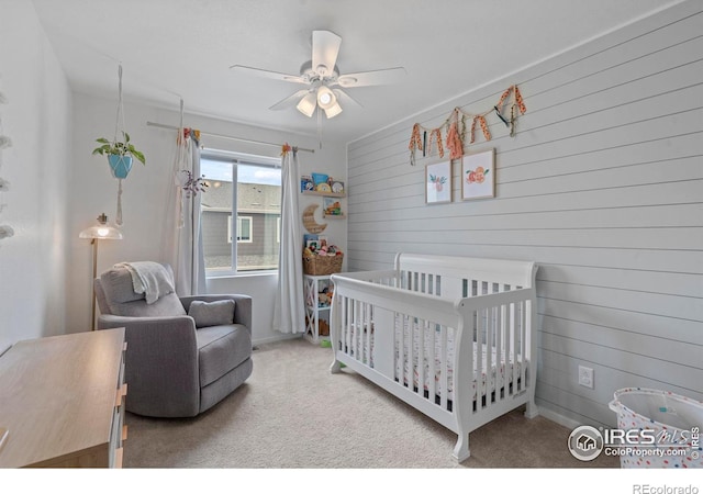 3644 Ronald Reagan Ave, Wellington, CO 80549 - carpeted bedroom featuring a nursery area, wooden walls, and a ceiling fan