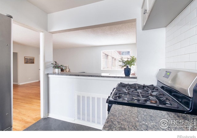 1100 Colorado Blvd Unit 305, Denver, CO 80206 - kitchen with stainless steel gas stove, white cabinets, tasteful backsplash, and wood finished floors