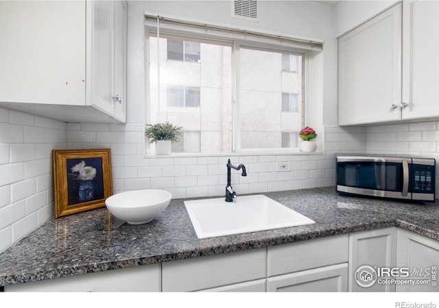 1100 Colorado Blvd Unit 305, Denver, CO 80206 - kitchen with stainless steel microwave, backsplash, white cabinets, and dark stone counters