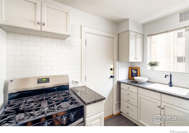 1100 Colorado Blvd Unit 305, Denver, CO 80206 - kitchen with stainless steel gas range oven, tasteful backsplash, white cabinetry, and dark stone counters