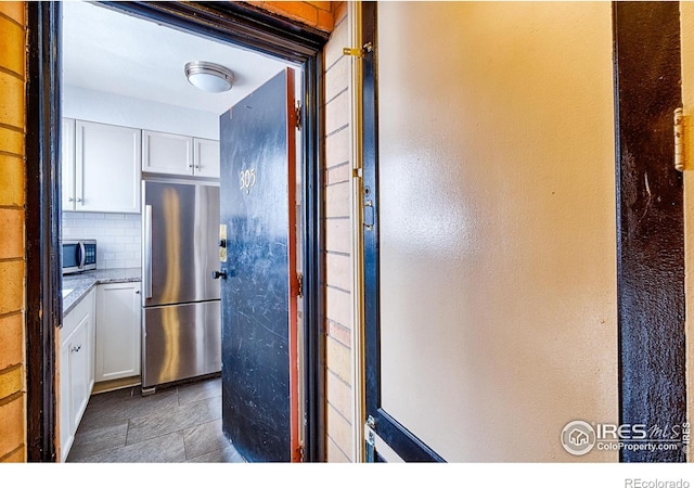 1100 Colorado Blvd Unit 305, Denver, CO 80206 - kitchen featuring stainless steel appliances, white cabinets, backsplash, light stone countertops, and a textured wall