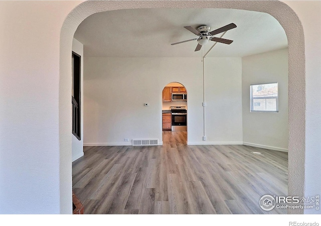 263 E 2nd St, Ault, CO 80610 - empty room with ceiling fan, arched walkways, and light wood-style floors