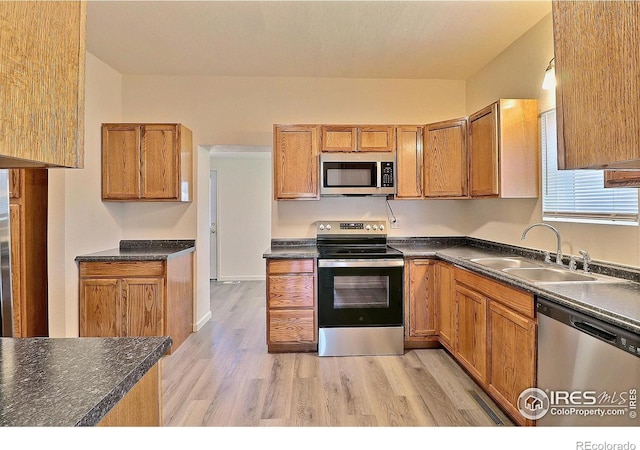 263 E 2nd St, Ault, CO 80610 - kitchen featuring appliances with stainless steel finishes, dark countertops, light wood-style floors, and brown cabinetry