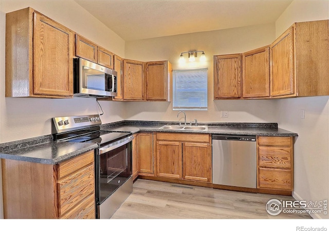 263 E 2nd St, Ault, CO 80610 - kitchen with appliances with stainless steel finishes, dark countertops, light wood-style floors, and brown cabinets