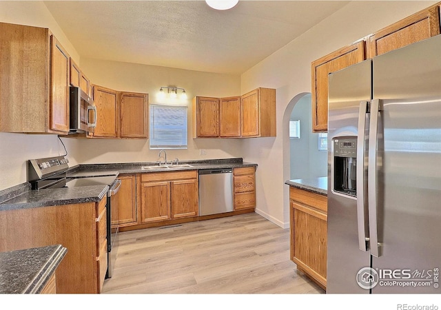 263 E 2nd St, Ault, CO 80610 - kitchen with stainless steel appliances, light wood-style floors, and brown cabinetry