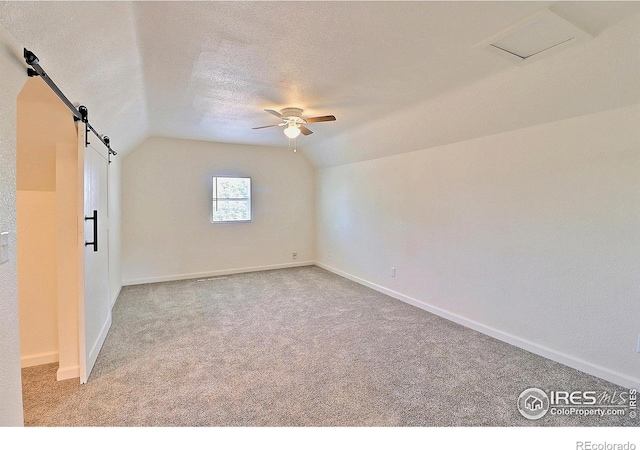263 E 2nd St, Ault, CO 80610 - bonus room featuring a barn door, vaulted ceiling, ceiling fan, carpet floors, and a textured ceiling