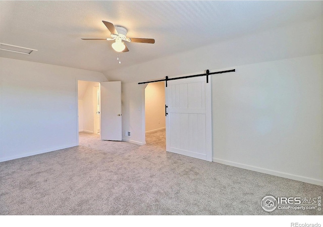 263 E 2nd St, Ault, CO 80610 - unfurnished bedroom featuring carpet floors, lofted ceiling, a barn door, and ceiling fan