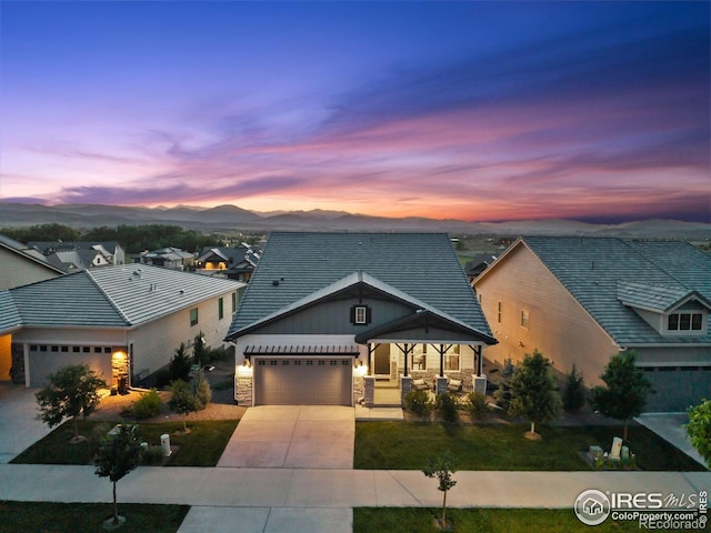 3315 Heron Lakes Pkwy, Berthoud, CO 80513 - view of front of home featuring an attached garage, stone siding, driveway, a mountain view, and covered porch