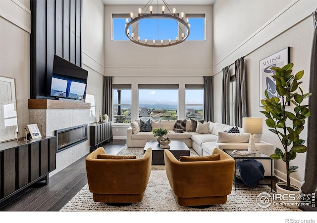 3315 Heron Lakes Pkwy, Berthoud, CO 80513 - living room with plenty of natural light, dark wood-style floors, a towering ceiling, a chandelier, and a fireplace