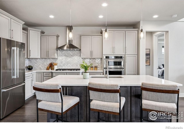 3315 Heron Lakes Pkwy, Berthoud, CO 80513 - kitchen with stainless steel appliances, wall chimney exhaust hood, backsplash, light countertops, and a kitchen island with sink