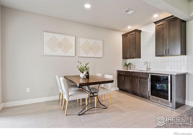 3315 Heron Lakes Pkwy, Berthoud, CO 80513 - kitchen featuring beverage cooler, dark brown cabinetry, light countertops, recessed lighting, and backsplash