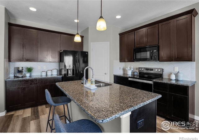 1384 S Growers Dr, Milliken, CO 80543 - kitchen with black appliances, light wood finished floors, dark brown cabinets, dark stone countertops, and recessed lighting