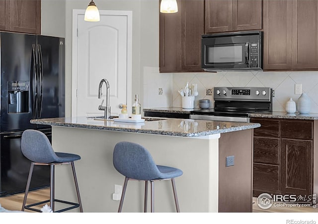 1384 S Growers Dr, Milliken, CO 80543 - kitchen featuring black appliances, dark brown cabinets, stone counters, and a breakfast bar