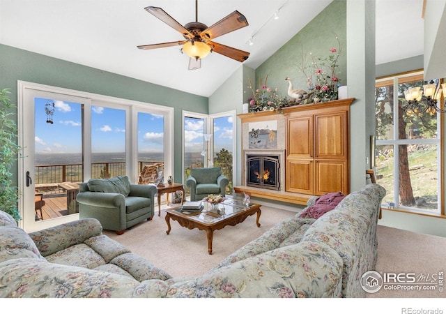6183 Red Hill Rd, Boulder, CO 80302 - carpeted living room featuring a ceiling fan, track lighting, a chandelier, a lit fireplace, and high vaulted ceiling