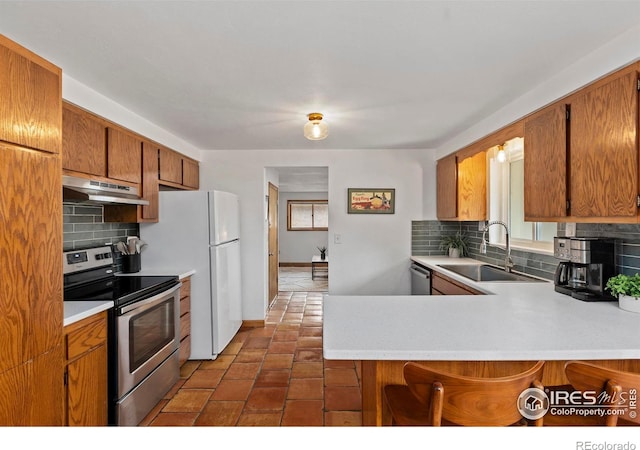 2306 Ptelea Ct, Loveland, CO 80538 - kitchen with stainless steel appliances, under cabinet range hood, light countertops, backsplash, and a peninsula