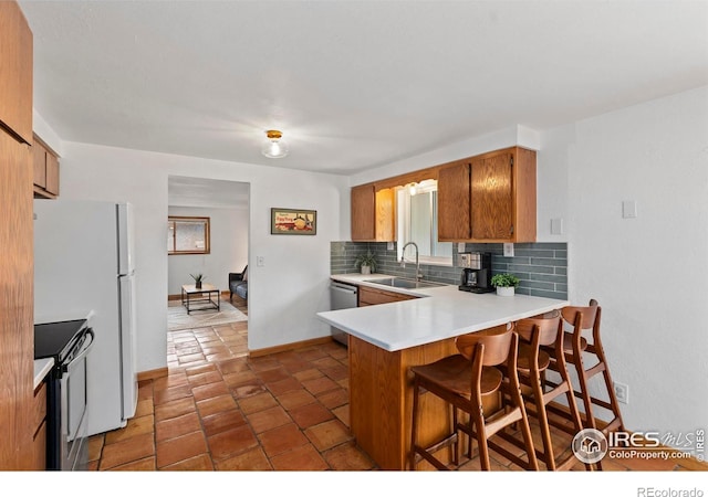 2306 Ptelea Ct, Loveland, CO 80538 - kitchen with stainless steel appliances, tasteful backsplash, light countertops, a peninsula, and brown cabinets