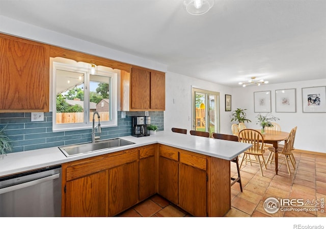 2306 Ptelea Ct, Loveland, CO 80538 - kitchen featuring stainless steel dishwasher, light countertops, tasteful backsplash, a peninsula, and brown cabinets