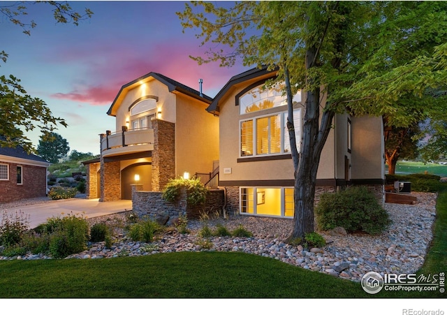 4926 Saint Andrews Ct, Loveland, CO 80537 - view of front of house featuring a balcony, stone siding, stucco siding, concrete driveway, and a lawn