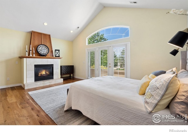 4926 Saint Andrews Ct, Loveland, CO 80537 - bedroom with access to exterior, wood finished floors, a tile fireplace, french doors, and high vaulted ceiling