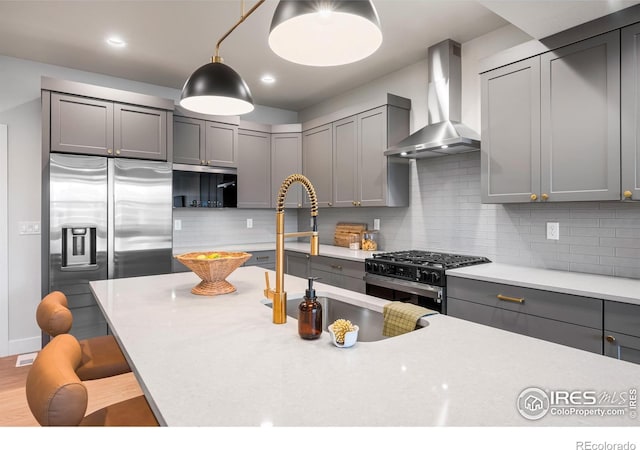 648 Greenspire Dr Unit 6, Windsor, CO 80550 - kitchen featuring wall chimney range hood, range with gas cooktop, stainless steel refrigerator with ice dispenser, gray cabinets, and a breakfast bar