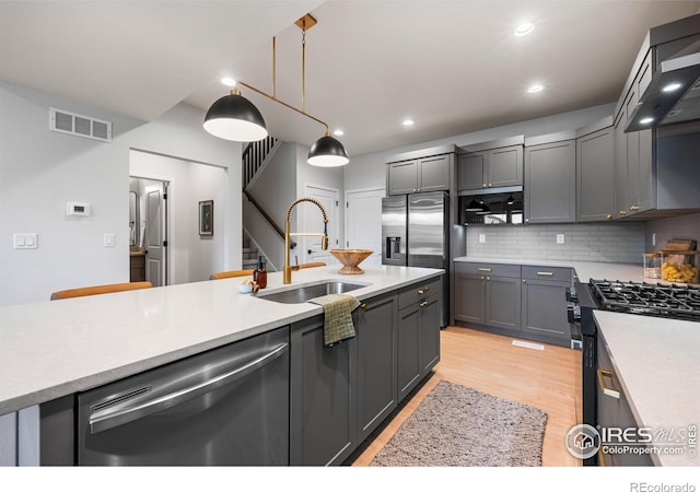 648 Greenspire Dr Unit 6, Windsor, CO 80550 - kitchen with appliances with stainless steel finishes, wall chimney range hood, light countertops, light wood-style floors, and decorative backsplash
