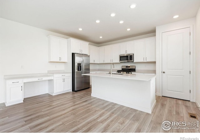 5226 Inland Ave, Firestone, CO 80504 - kitchen featuring appliances with stainless steel finishes, light wood-type flooring, light countertops, white cabinetry, and an island with sink