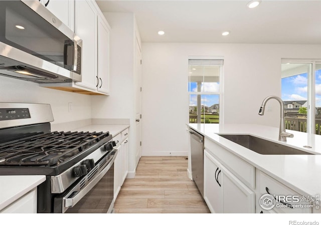 5226 Inland Ave, Firestone, CO 80504 - kitchen featuring stainless steel appliances, light wood-type flooring, plenty of natural light, white cabinetry, and recessed lighting