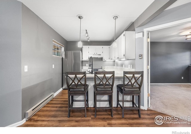 3531 Windmill Dr Unit 3, Fort Collins, CO 80526 - kitchen featuring a baseboard radiator, freestanding refrigerator, a peninsula, white cabinets, and a kitchen breakfast bar