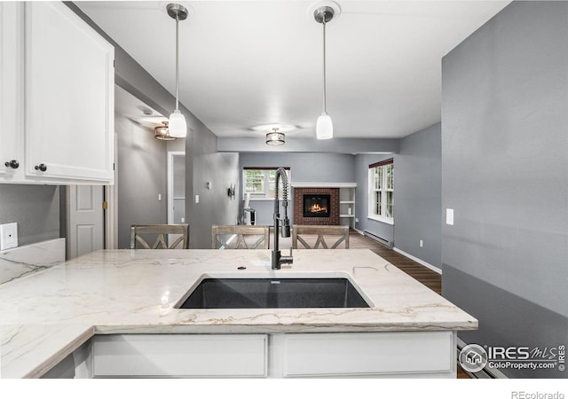 3531 Windmill Dr Unit 3, Fort Collins, CO 80526 - kitchen featuring open floor plan, white cabinets, light stone counters, a fireplace, and wood finished floors