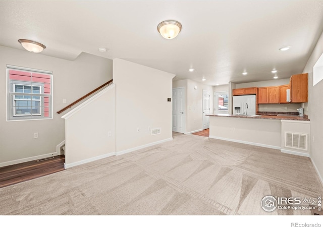 67 Quail Rd, Longmont, CO 80501 - unfurnished living room featuring light carpet, stairs, and recessed lighting