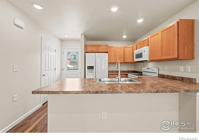 67 Quail Rd, Longmont, CO 80501 - kitchen featuring white appliances, a peninsula, dark wood-type flooring, and recessed lighting