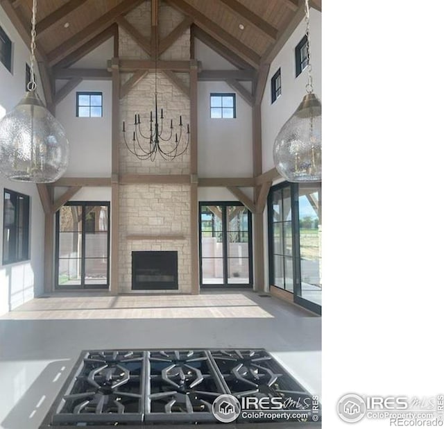 917 Latigo Loop, Lafayette, CO 80026 - unfurnished living room with high vaulted ceiling, a chandelier, beamed ceiling, healthy amount of natural light, and a fireplace