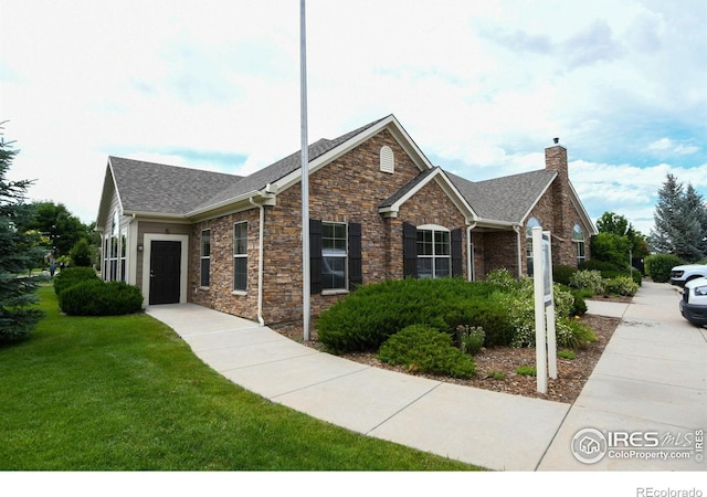 2421 Santa Fe Dr Unit B, Longmont, CO 80504 - view of front of house featuring a chimney, a front lawn, stone siding, and a shingled roof