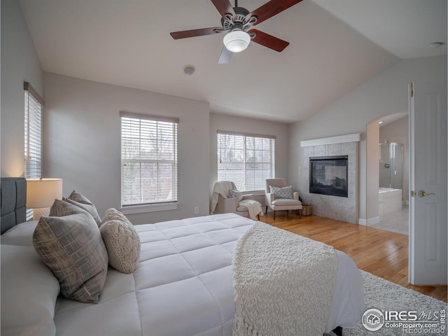 2946 Shoshone Trl, Lafayette, CO 80026 - bedroom with wood finished floors, multiple windows, vaulted ceiling, a fireplace, and connected bathroom