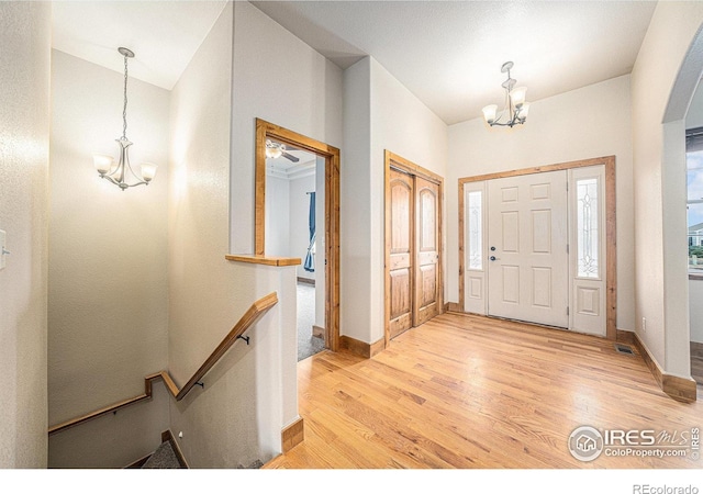 20199 Leola Way, Eaton, CO 80615 - entryway featuring a chandelier, light wood-type flooring, vaulted ceiling, and arched walkways
