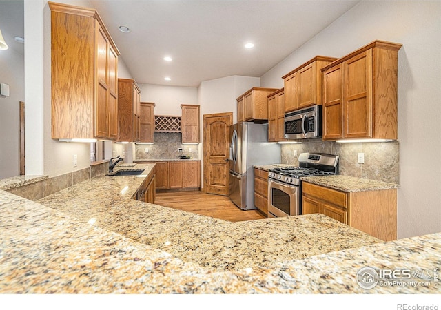 20199 Leola Way, Eaton, CO 80615 - kitchen with appliances with stainless steel finishes, light stone countertops, tasteful backsplash, light wood-style floors, and recessed lighting