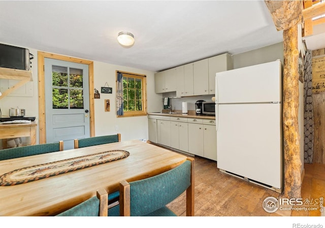 11614 Peak To Peak Hwy, Allenspark, CO 80510 - kitchen with freestanding refrigerator, light wood-type flooring, stainless steel microwave, white cabinetry, and light countertops