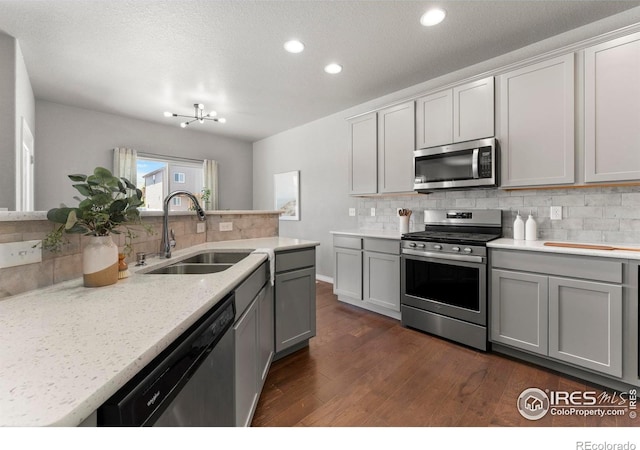 5612 Osbourne Dr, Windsor, CO 80550 - kitchen featuring appliances with stainless steel finishes, tasteful backsplash, gray cabinets, dark wood-style floors, and recessed lighting