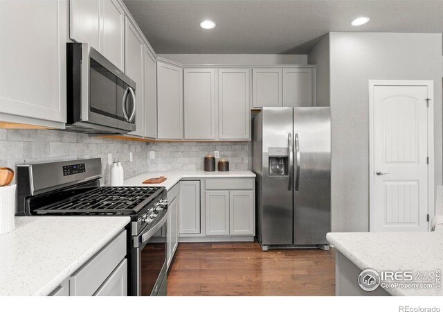 5612 Osbourne Dr, Windsor, CO 80550 - kitchen with appliances with stainless steel finishes, dark wood finished floors, decorative backsplash, and recessed lighting