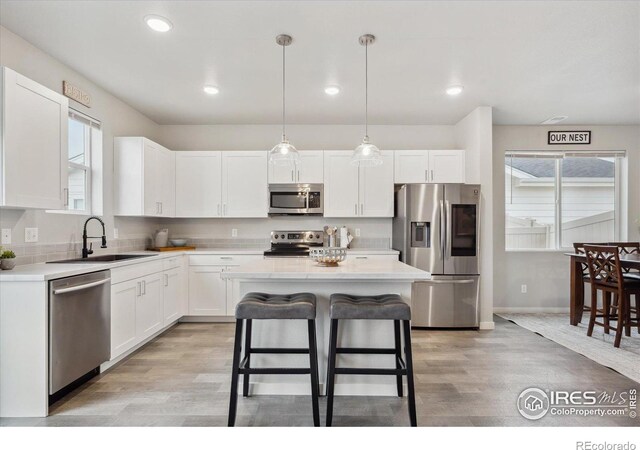 362 Bozeman Trl, Ault, CO 80610 - kitchen featuring appliances with stainless steel finishes, white cabinets, light countertops, light wood-type flooring, and pendant lighting