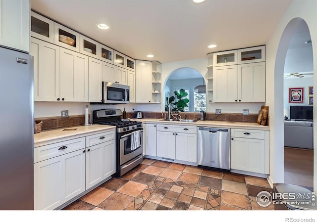 1149 Quince Ave, Boulder, CO 80304 - kitchen featuring stainless steel appliances, open shelves, arched walkways, light stone finish floors, and glass insert cabinets