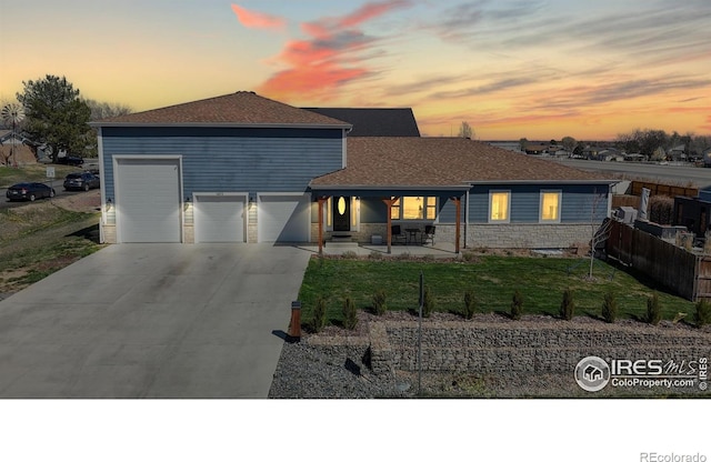 1403 Crestridge Dr, Loveland, CO 80537 - view of front of property with driveway, stone siding, an attached garage, a shingled roof, and a porch