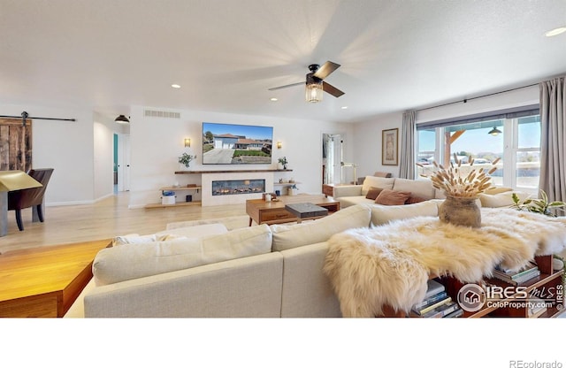 1403 Crestridge Dr, Loveland, CO 80537 - living room with a barn door, a ceiling fan, wood finished floors, a glass covered fireplace, and recessed lighting