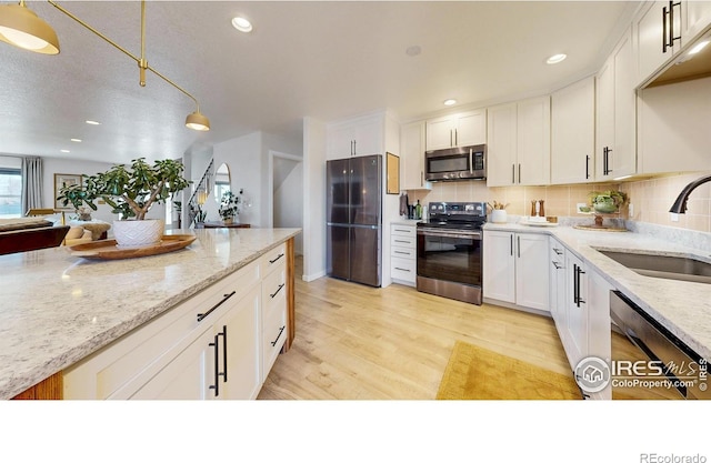 1403 Crestridge Dr, Loveland, CO 80537 - kitchen with stainless steel appliances, white cabinets, backsplash, light wood-style flooring, and recessed lighting