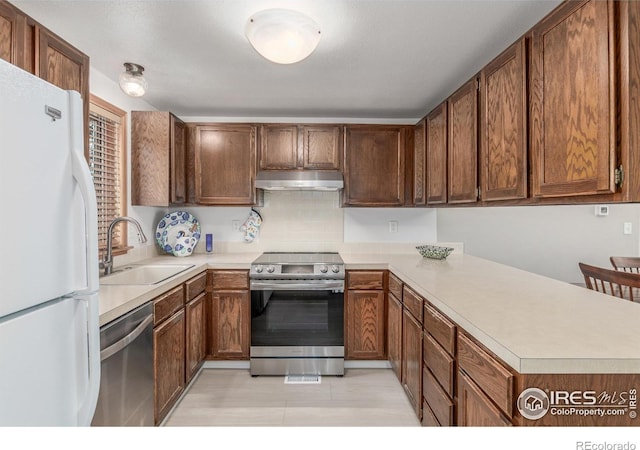 2707 W Stuart St, Fort Collins, CO 80526 - kitchen featuring appliances with stainless steel finishes, under cabinet range hood, light countertops, light tile patterned floors, and a peninsula