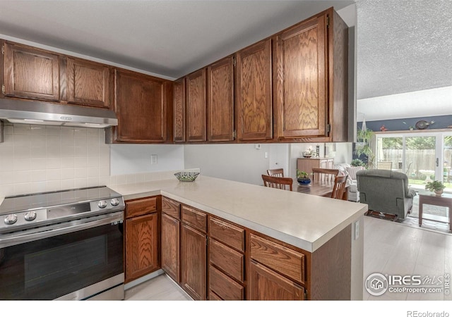 2707 W Stuart St, Fort Collins, CO 80526 - kitchen with stainless steel range with electric stovetop, under cabinet range hood, a peninsula, light countertops, and decorative backsplash