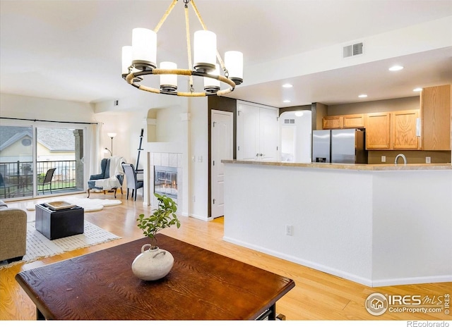 1122 Olympia Ave Unit 12H, Longmont, CO 80504 - dining area featuring a chandelier, light wood-type flooring, recessed lighting, and a tile fireplace