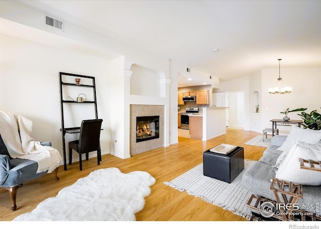 1122 Olympia Ave Unit 12H, Longmont, CO 80504 - living room featuring a chandelier, vaulted ceiling, a fireplace, and light wood-style flooring