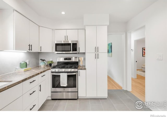 2025 Grape Ave, Boulder, CO 80304 - kitchen with stainless steel appliances, white cabinets, recessed lighting, light tile patterned floors, and light stone counters